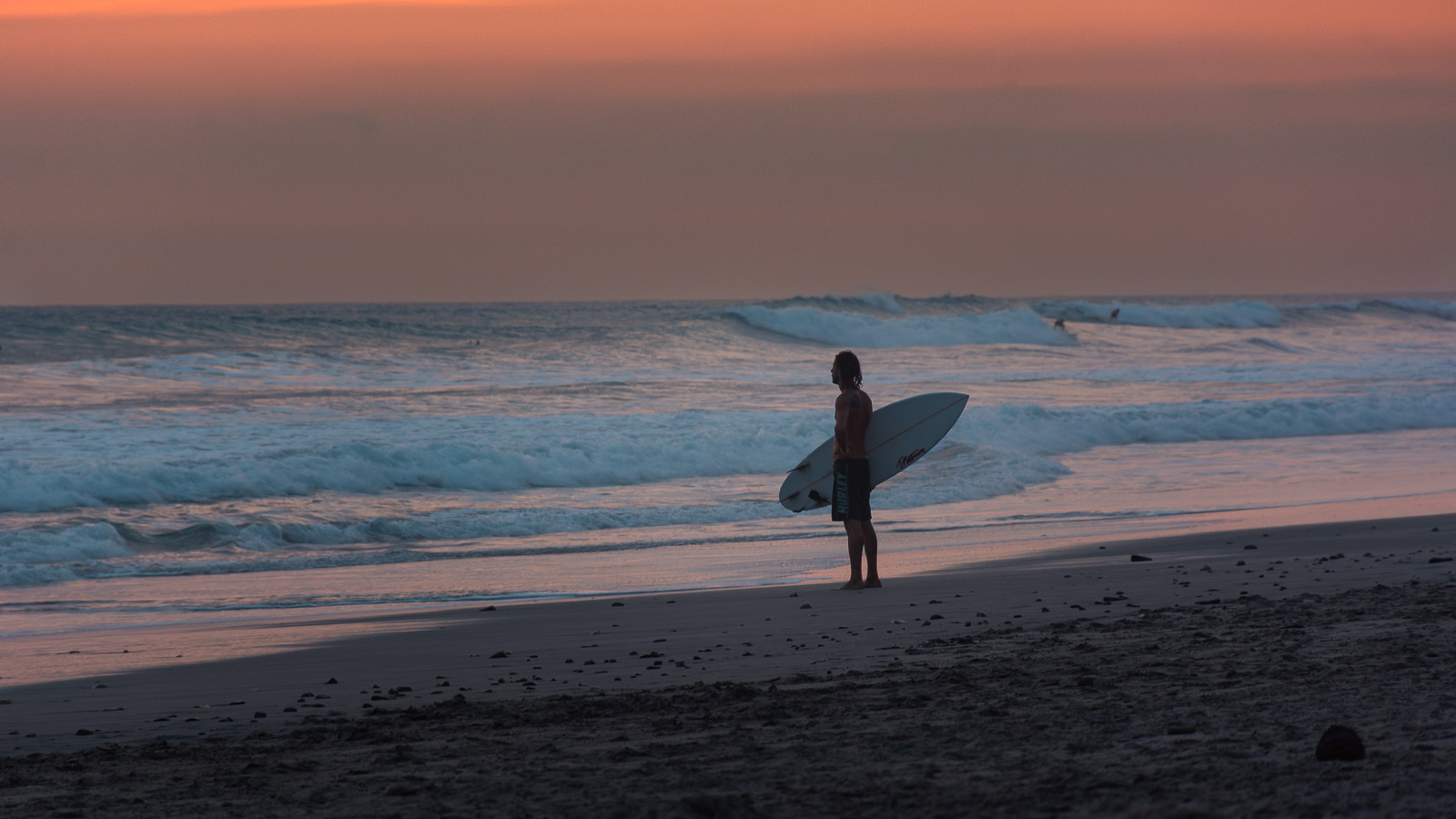 Surfer con tabla caminando por playa de Santa Teresa, Costa Rica
