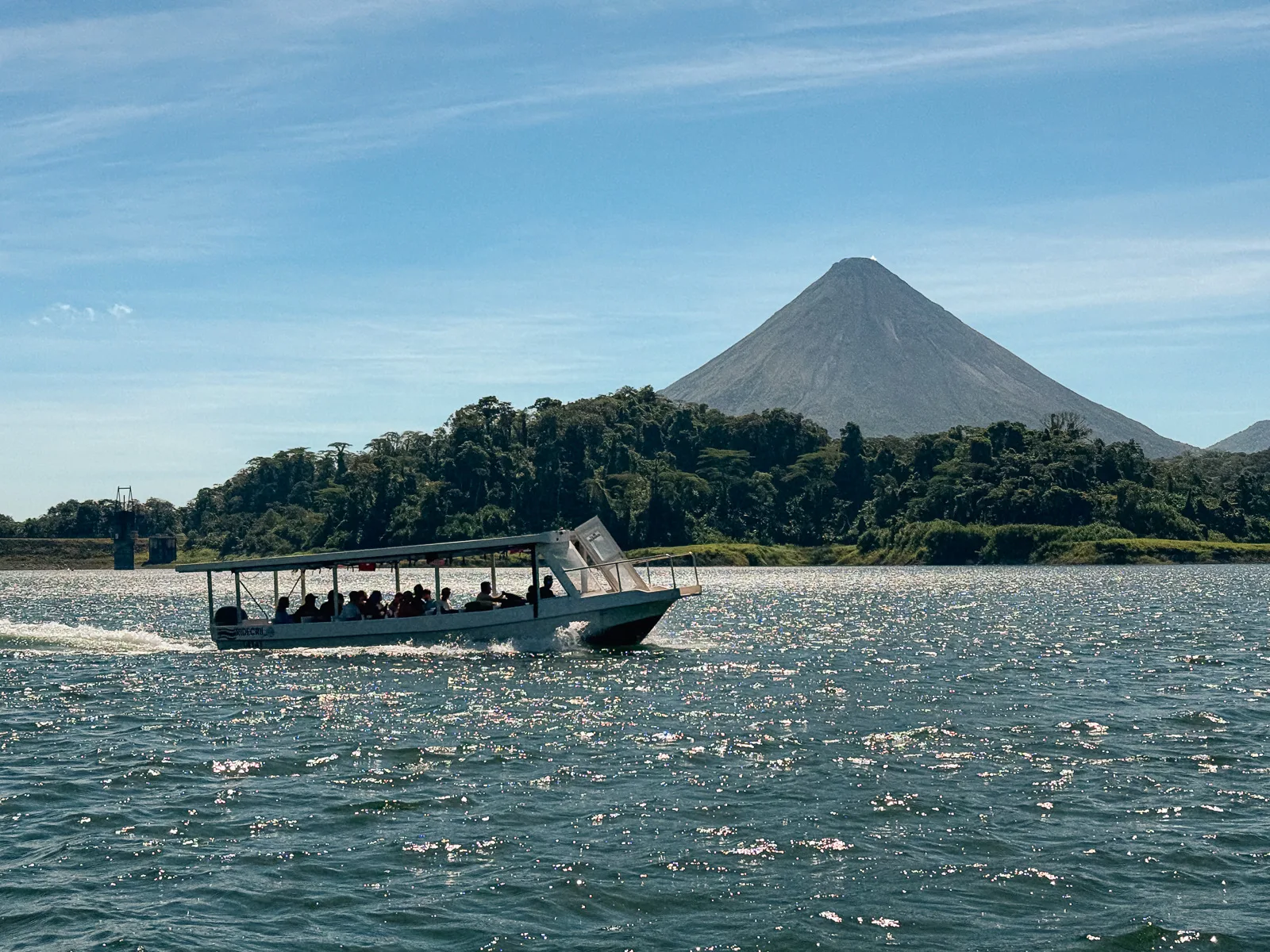 Lancha navegando con el volcán Arenal de fondo