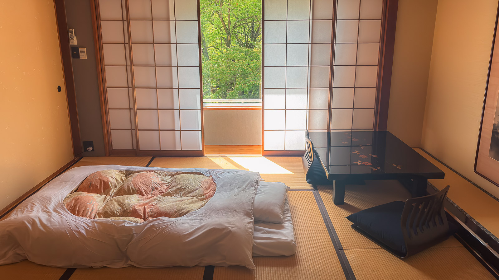 Habitación con tatami y futón en Yoshiike Ryokan con vista al jardín.